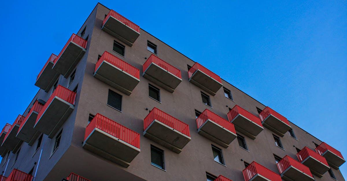 Low-angle view of a Vienna residential building with red balconies against a clear blue sky.