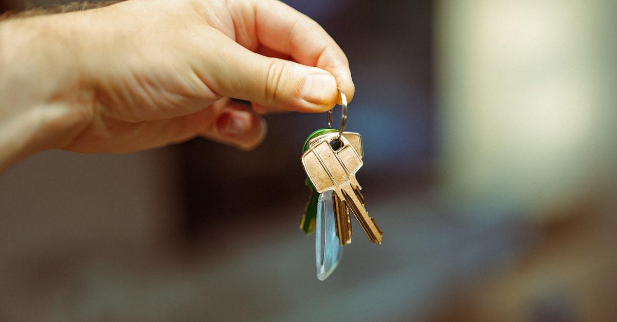 A close-up image of a hand holding a keyring with several house keys, symbolizing real estate and home ownership.